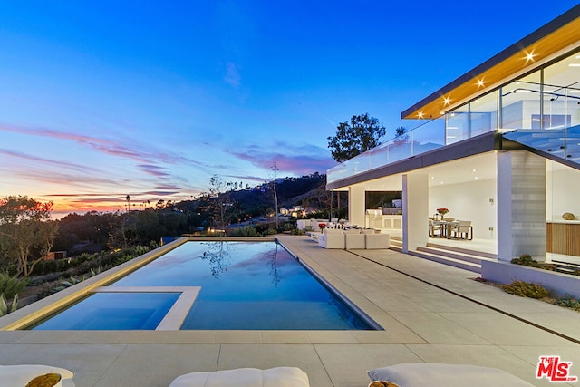 pool at dusk featuring a patio area