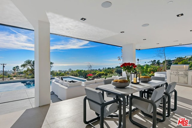 view of patio / terrace with a swimming pool with hot tub, a grill, and an outdoor kitchen