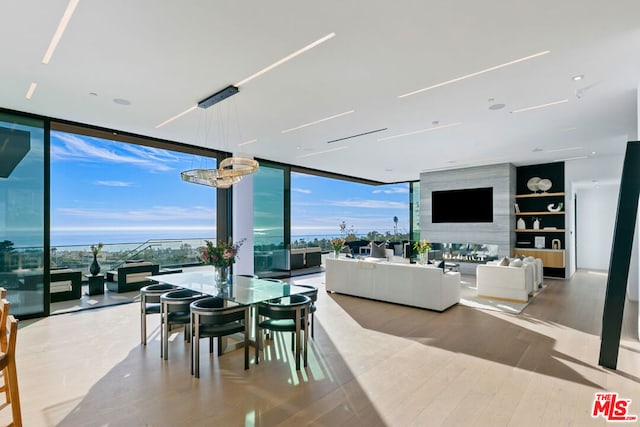 dining area with a high end fireplace, floor to ceiling windows, and light hardwood / wood-style flooring