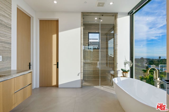 bathroom with tile patterned flooring, a wall of windows, vanity, and shower with separate bathtub