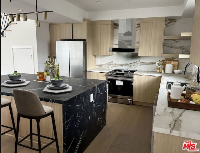 kitchen with sink, refrigerator, stainless steel gas range oven, a kitchen island, and wall chimney exhaust hood