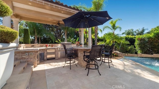 view of patio with pool water feature, ceiling fan, exterior kitchen, and an outdoor bar