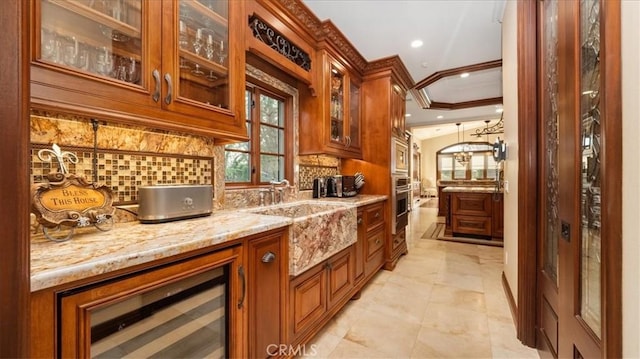 bar featuring sink, crown molding, appliances with stainless steel finishes, light stone counters, and decorative backsplash