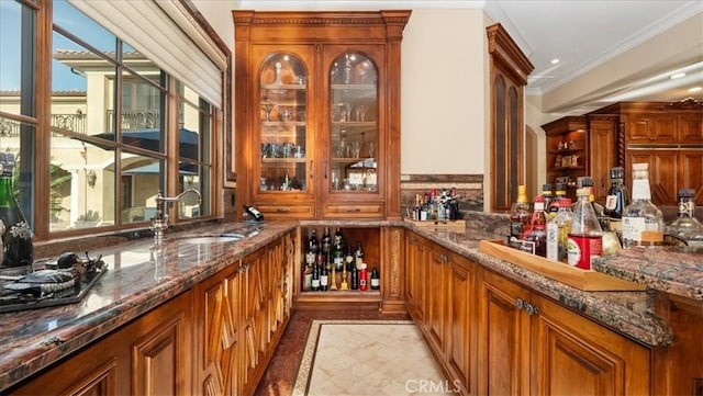 bar featuring sink, crown molding, and dark stone counters