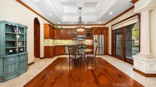 kitchen with backsplash, stainless steel appliances, decorative columns, ornamental molding, and decorative light fixtures