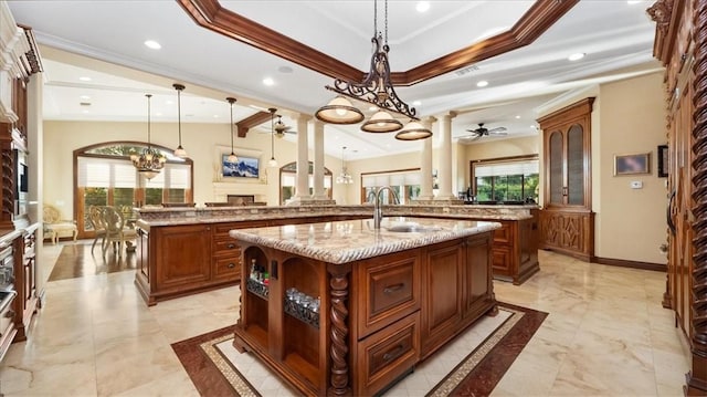 kitchen with ceiling fan with notable chandelier, decorative light fixtures, sink, a kitchen island with sink, and kitchen peninsula