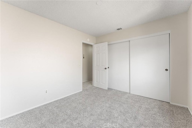 unfurnished bedroom with a textured ceiling, a closet, and carpet floors