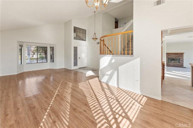 unfurnished living room featuring lofted ceiling, hardwood / wood-style floors, and a notable chandelier