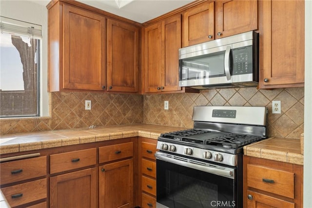 kitchen with tile counters, decorative backsplash, and appliances with stainless steel finishes