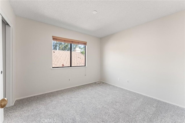 carpeted empty room with a textured ceiling