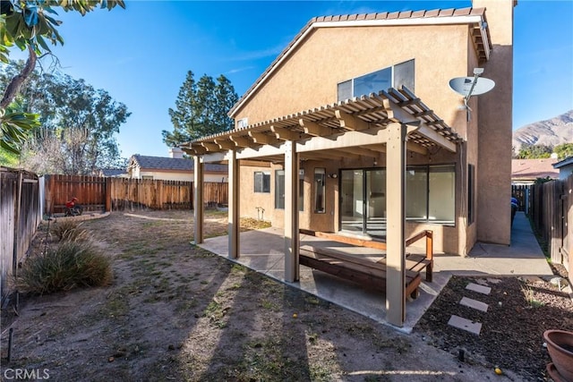 back of house with a pergola, a mountain view, and a patio