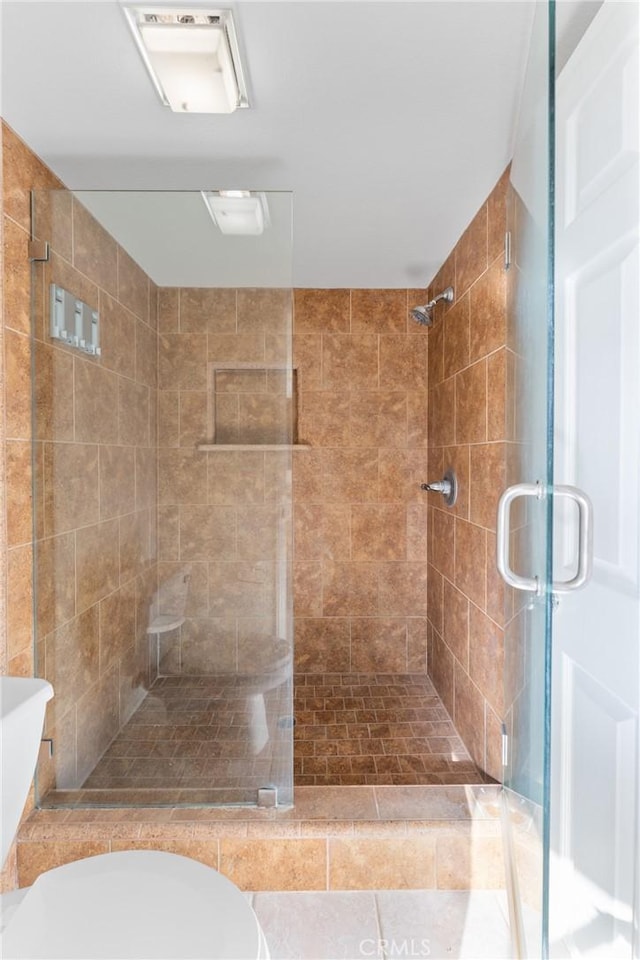 bathroom with toilet, tile patterned floors, and a shower with shower door