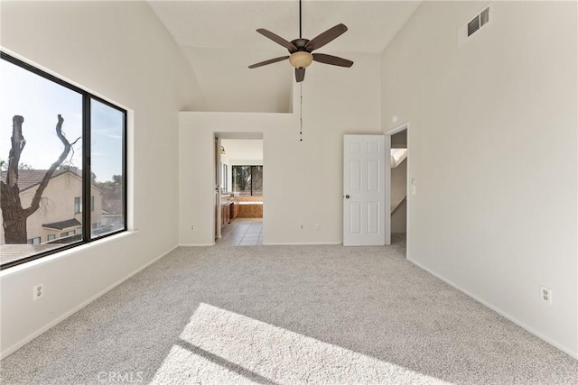 carpeted empty room with ceiling fan and high vaulted ceiling