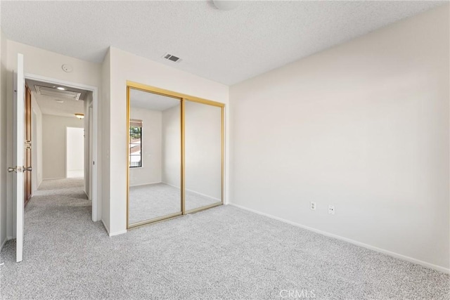 unfurnished bedroom with light carpet, a closet, and a textured ceiling