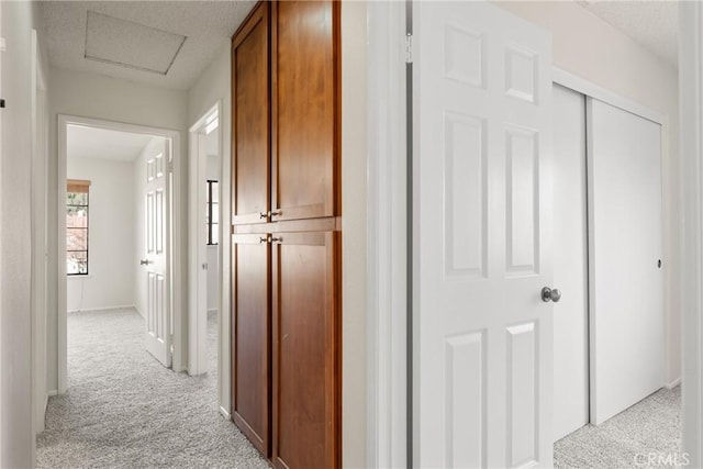 hallway featuring light colored carpet and a textured ceiling