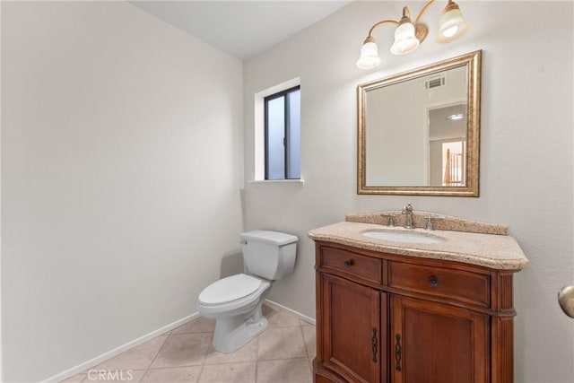 bathroom with toilet, vanity, and tile patterned flooring