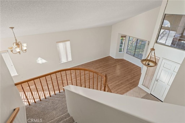 stairs featuring a textured ceiling, lofted ceiling, and an inviting chandelier