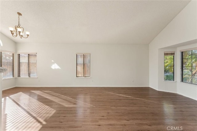 unfurnished room featuring dark hardwood / wood-style floors, lofted ceiling, and a chandelier