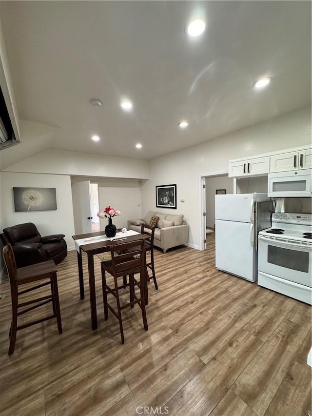 dining room with vaulted ceiling and hardwood / wood-style floors