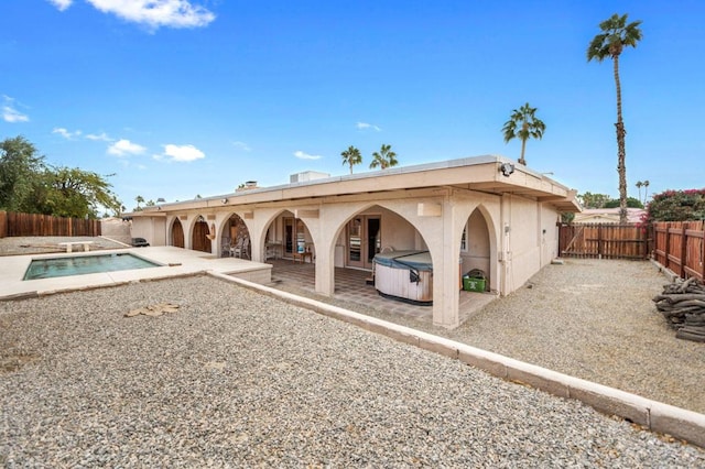 rear view of house with a swimming pool with hot tub and a patio