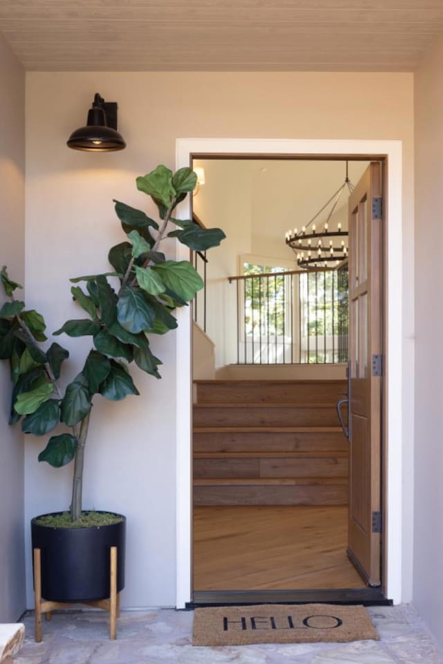 stairs with concrete floors, wood ceiling, and an inviting chandelier