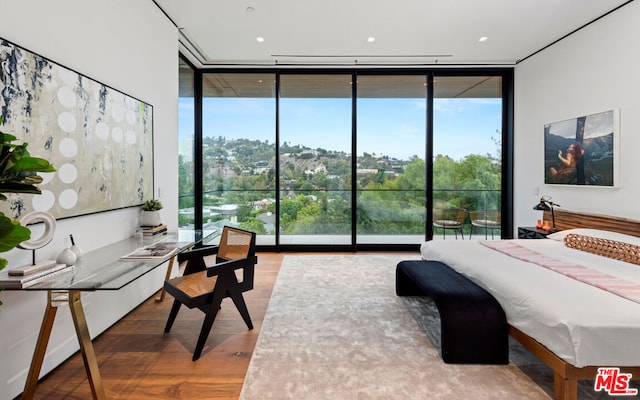 bedroom with multiple windows, wood-type flooring, and a wall of windows