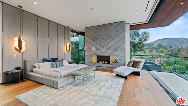 living room featuring a mountain view, a high end fireplace, expansive windows, and light wood-type flooring