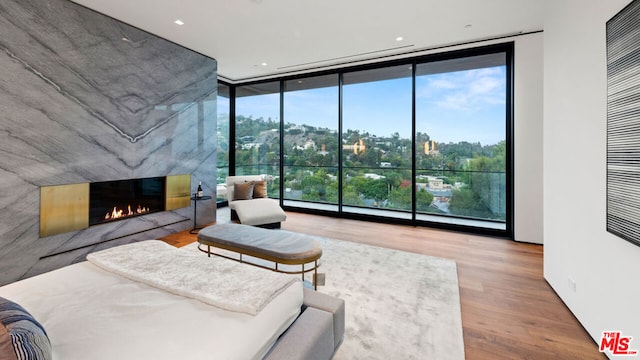 bedroom featuring a high end fireplace, floor to ceiling windows, wood-type flooring, and multiple windows