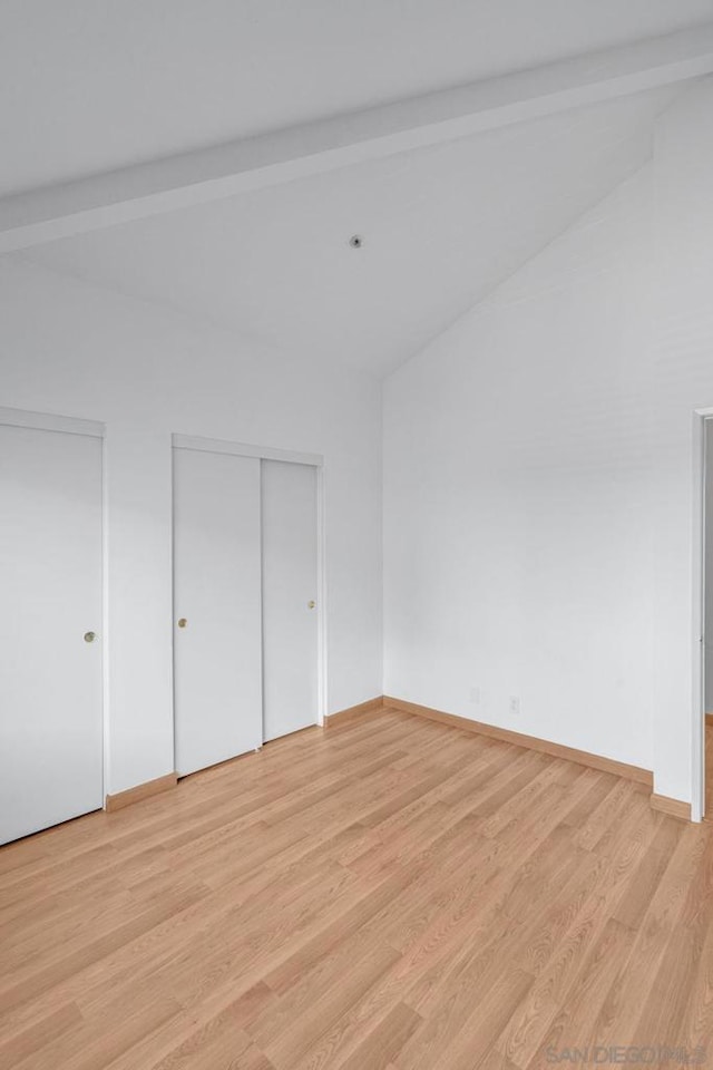 unfurnished bedroom featuring light hardwood / wood-style floors and beamed ceiling