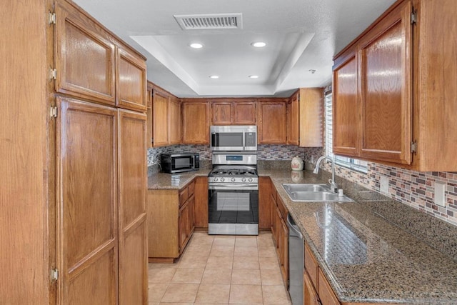 kitchen with stainless steel appliances, tasteful backsplash, a tray ceiling, and sink