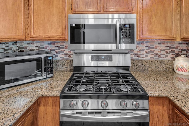 kitchen featuring tasteful backsplash, light stone counters, and stainless steel appliances