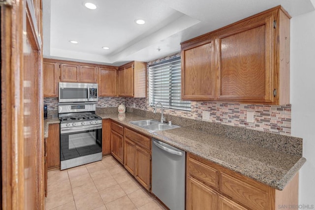 kitchen featuring light tile patterned flooring, appliances with stainless steel finishes, a raised ceiling, and sink