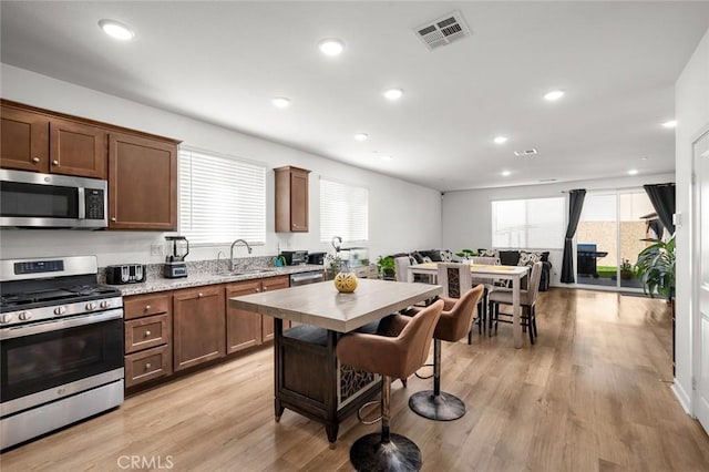 5097 Larkspur Rd, Banning, CA 92220 - kitchen featuring appliances with stainless steel finishes, a sink, recessed lighting, light wood-type flooring, and light stone counters