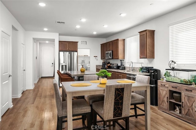 kitchen with stainless steel appliances, a healthy amount of sunlight, light hardwood / wood-style flooring, and a center island