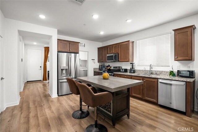 5097 Larkspur Rd, Banning, CA 92220 - kitchen with stainless steel appliances, light wood-style floors, washer / clothes dryer, recessed lighting, and a center island