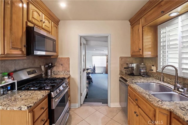 kitchen featuring light stone countertops, appliances with stainless steel finishes, tasteful backsplash, sink, and light tile patterned flooring