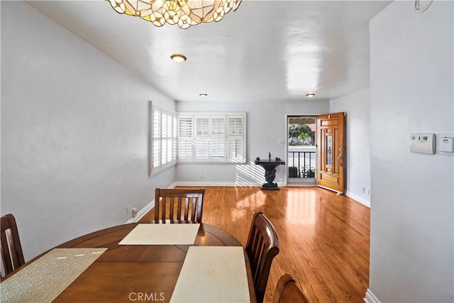 dining room with a healthy amount of sunlight, wood-type flooring, and a notable chandelier