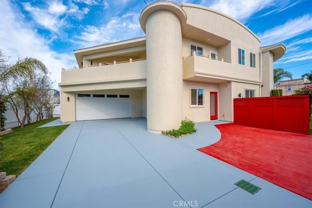 view of front of house with fence, a balcony, and stucco siding