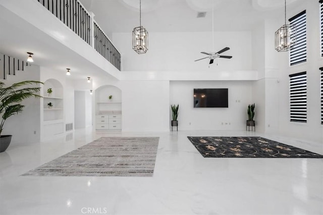 unfurnished living room featuring ceiling fan, built in features, and a high ceiling