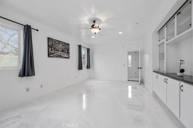 interior space with dark countertops, a healthy amount of sunlight, ceiling fan, and white cabinetry