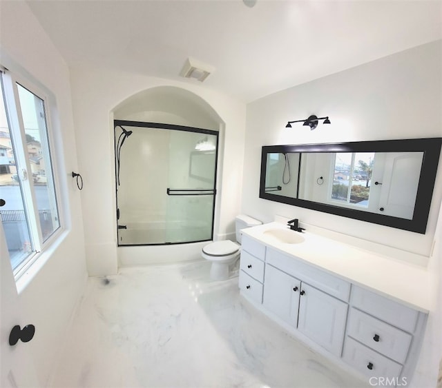 full bathroom featuring toilet, bath / shower combo with glass door, a healthy amount of sunlight, and vanity