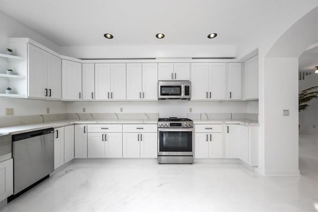 kitchen with light stone countertops, white cabinetry, and stainless steel appliances