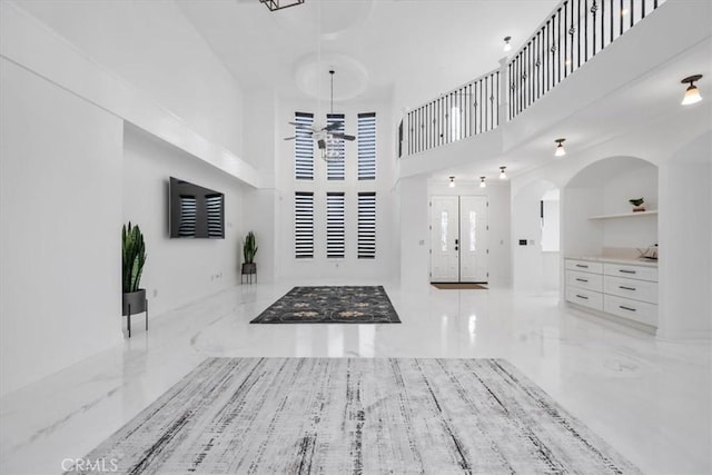 foyer with ceiling fan, a towering ceiling, and french doors