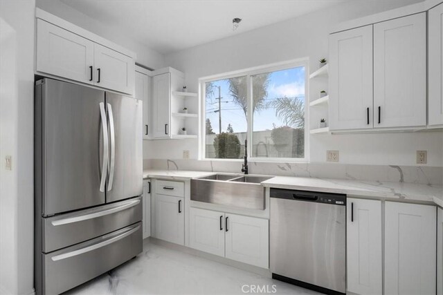 kitchen featuring light stone counters, white cabinets, appliances with stainless steel finishes, and sink