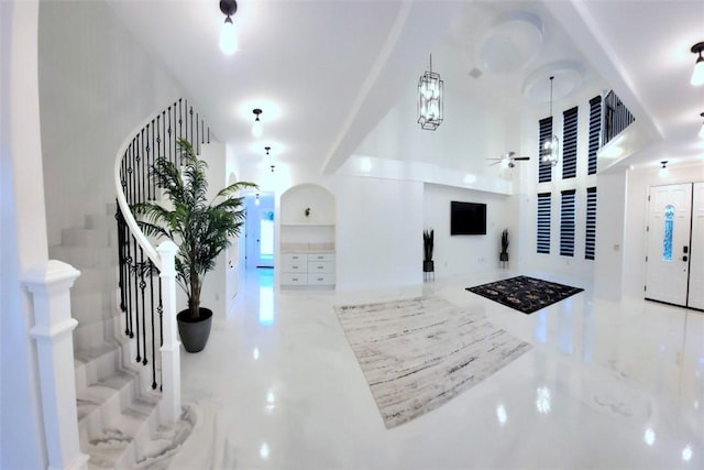 interior space with arched walkways, ceiling fan, and stairway