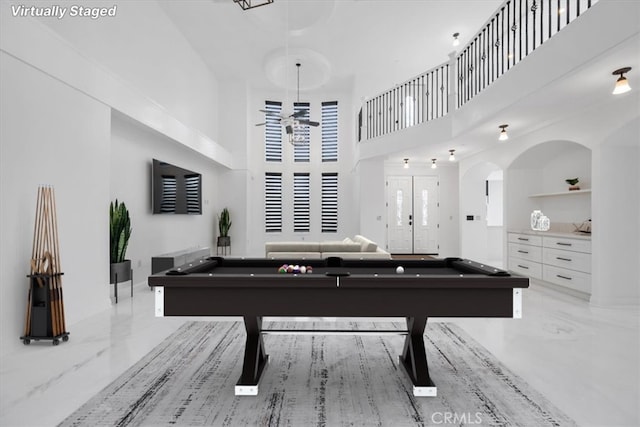 recreation room with a towering ceiling, marble finish floor, and billiards