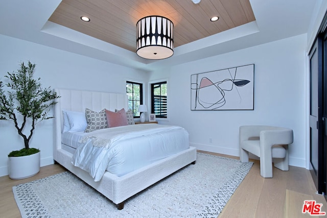 bedroom featuring wood ceiling, hardwood / wood-style flooring, and a tray ceiling