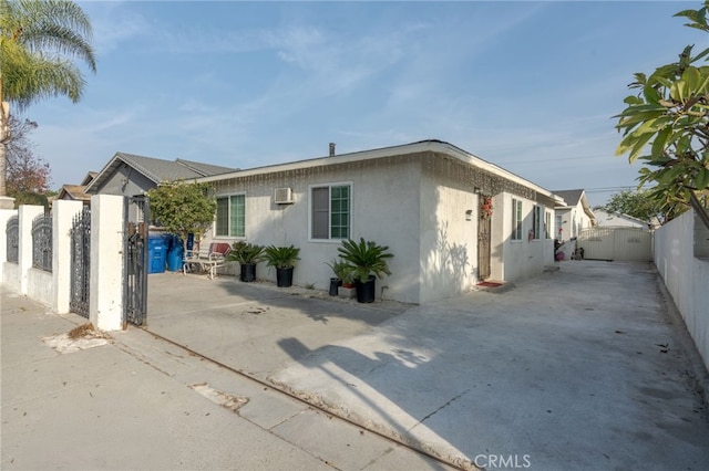 exterior space with a patio area and a wall mounted air conditioner