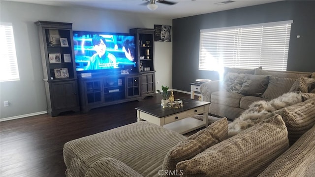 living room with dark wood-type flooring, ceiling fan, and a healthy amount of sunlight