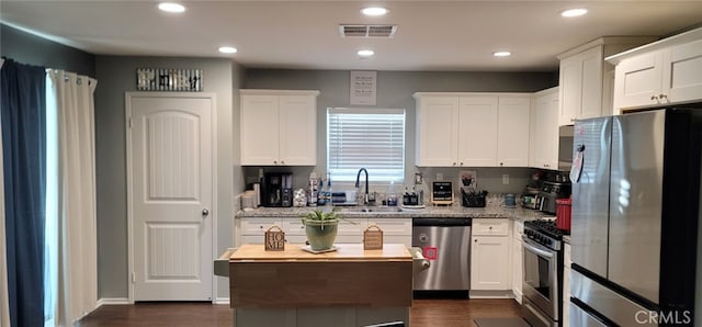 kitchen with stainless steel appliances, sink, white cabinets, and light stone counters